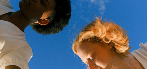 3 visages de femme vu du bas sur un fond de ciel bleu