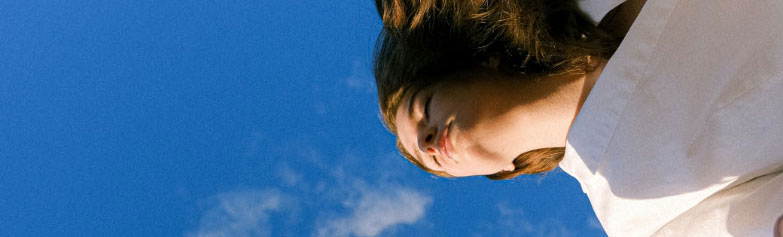 visage d'une femme vue du bas sur fond de ciel bleu
